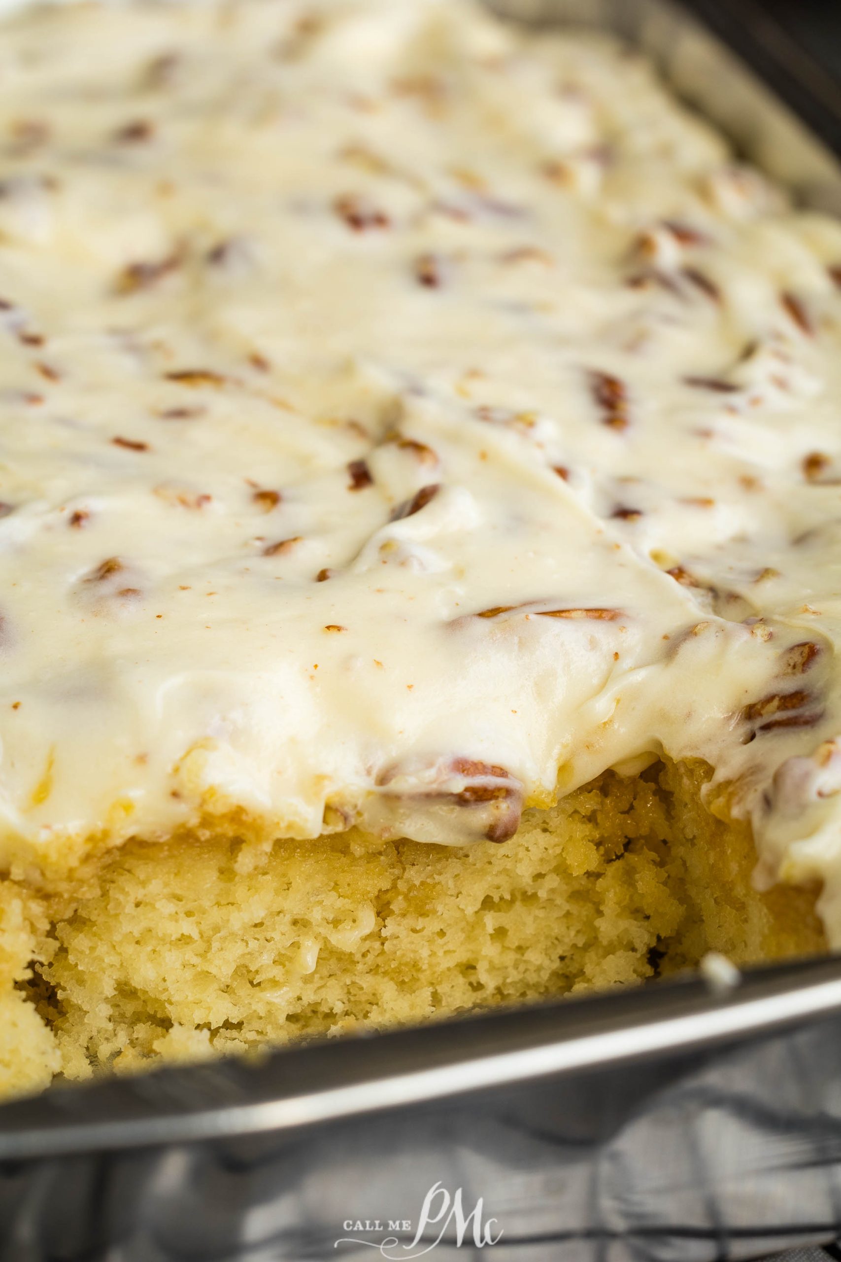 A pan of Elvis Presley Pineapple Poke Cake with icing and pecans.