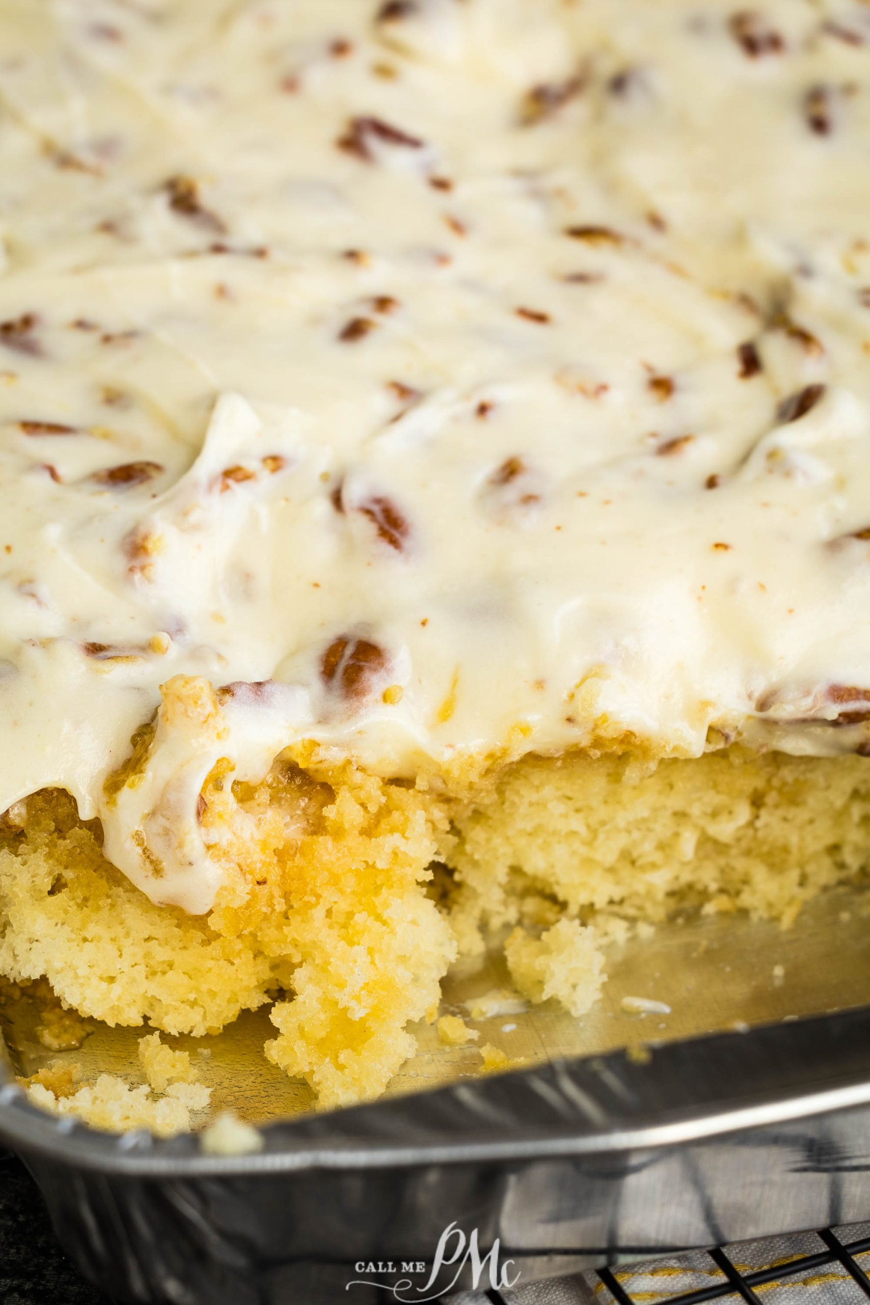 A slice of pecan cake in a pan on a cooling rack.