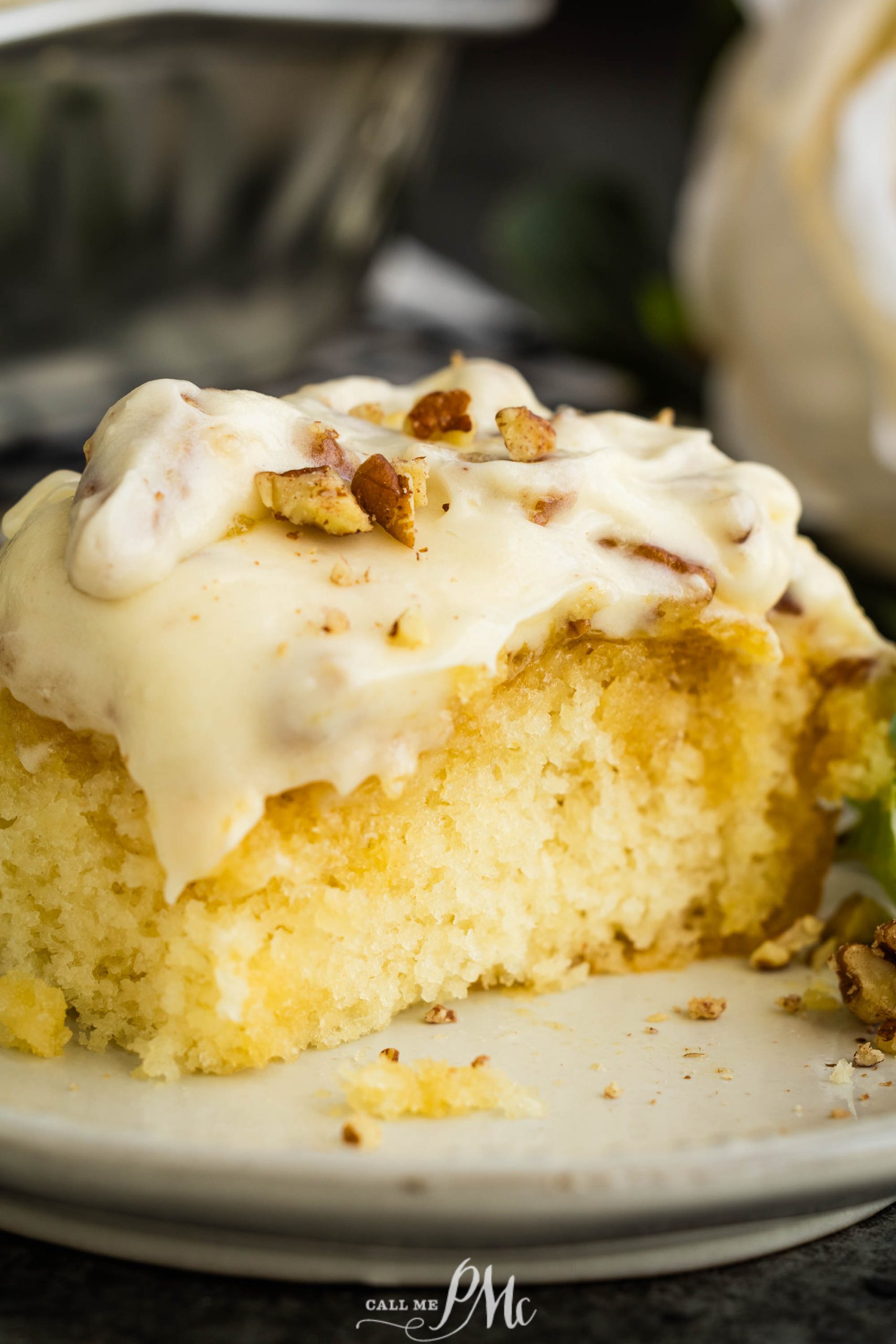 A slice of cake with frosting and pecans on a plate.