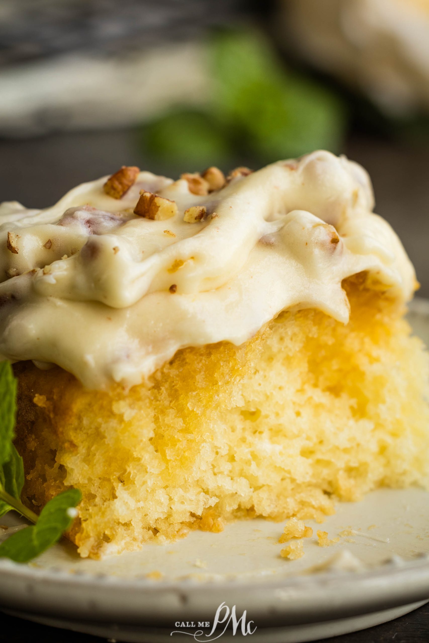 A slice of Elvis Presley Pineapple Poke Cake with icing and mint leaves on a plate.