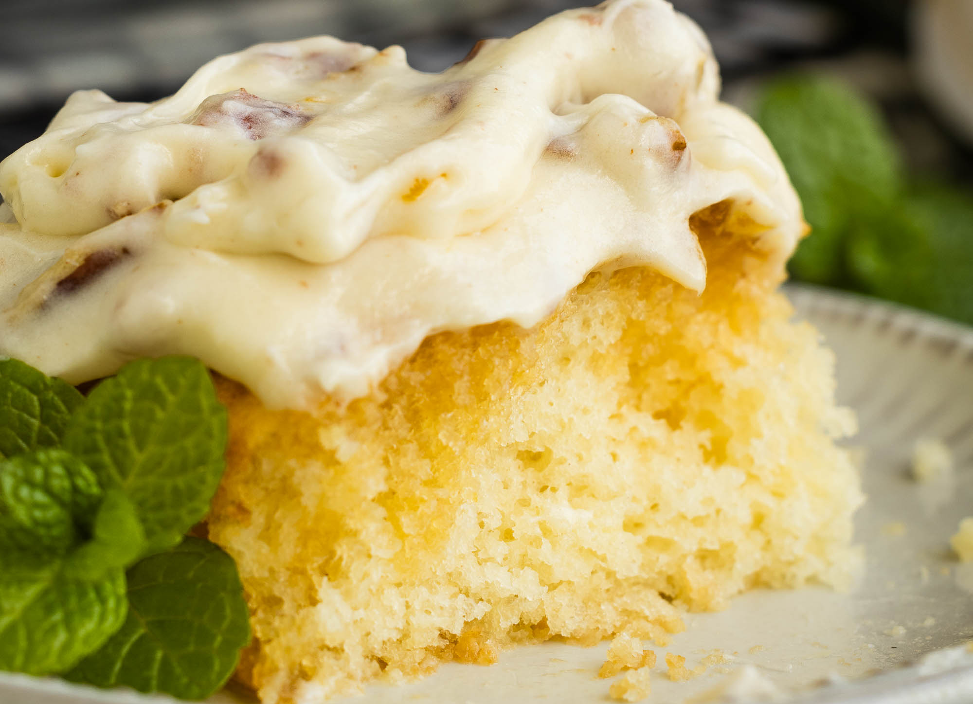 An Elvis Presley inspired Pineapple Poke Cake, complete with icing and mint leaves, delicately presented on a plate.