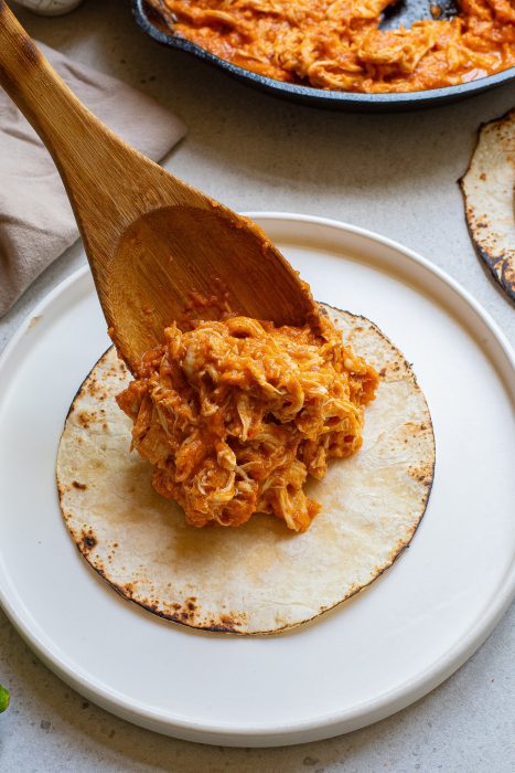 Stovetop Chicken Tinga Recipe on a white plate with a wooden spoon.