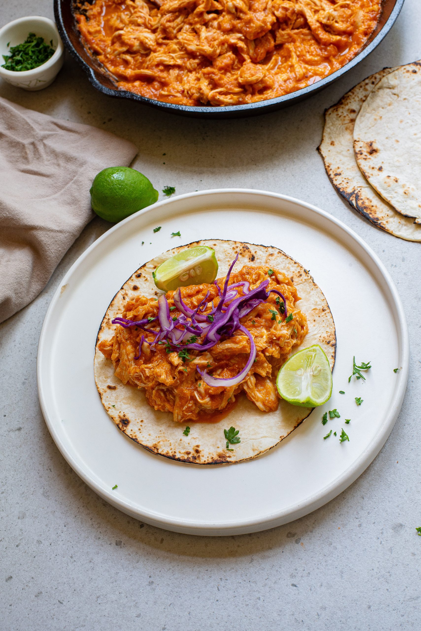 Mexican chicken tacos on a plate next to a skillet.
