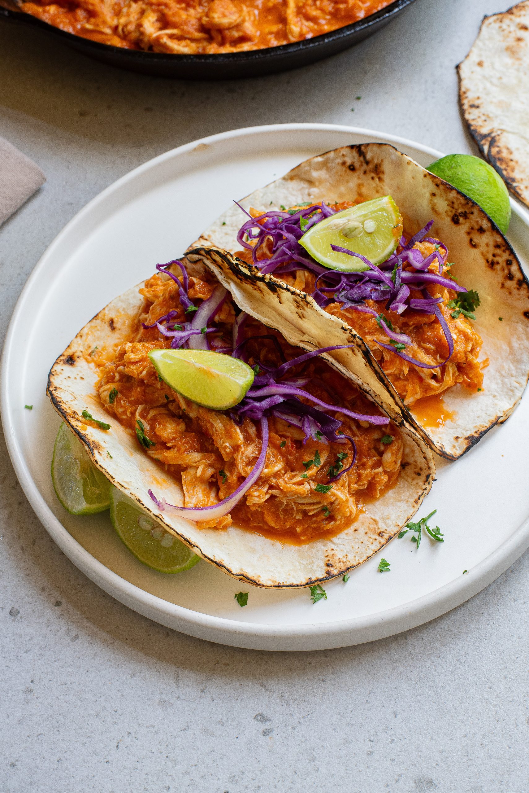 Stovetop Chicken Tinga Recipe on a plate next to a skillet.