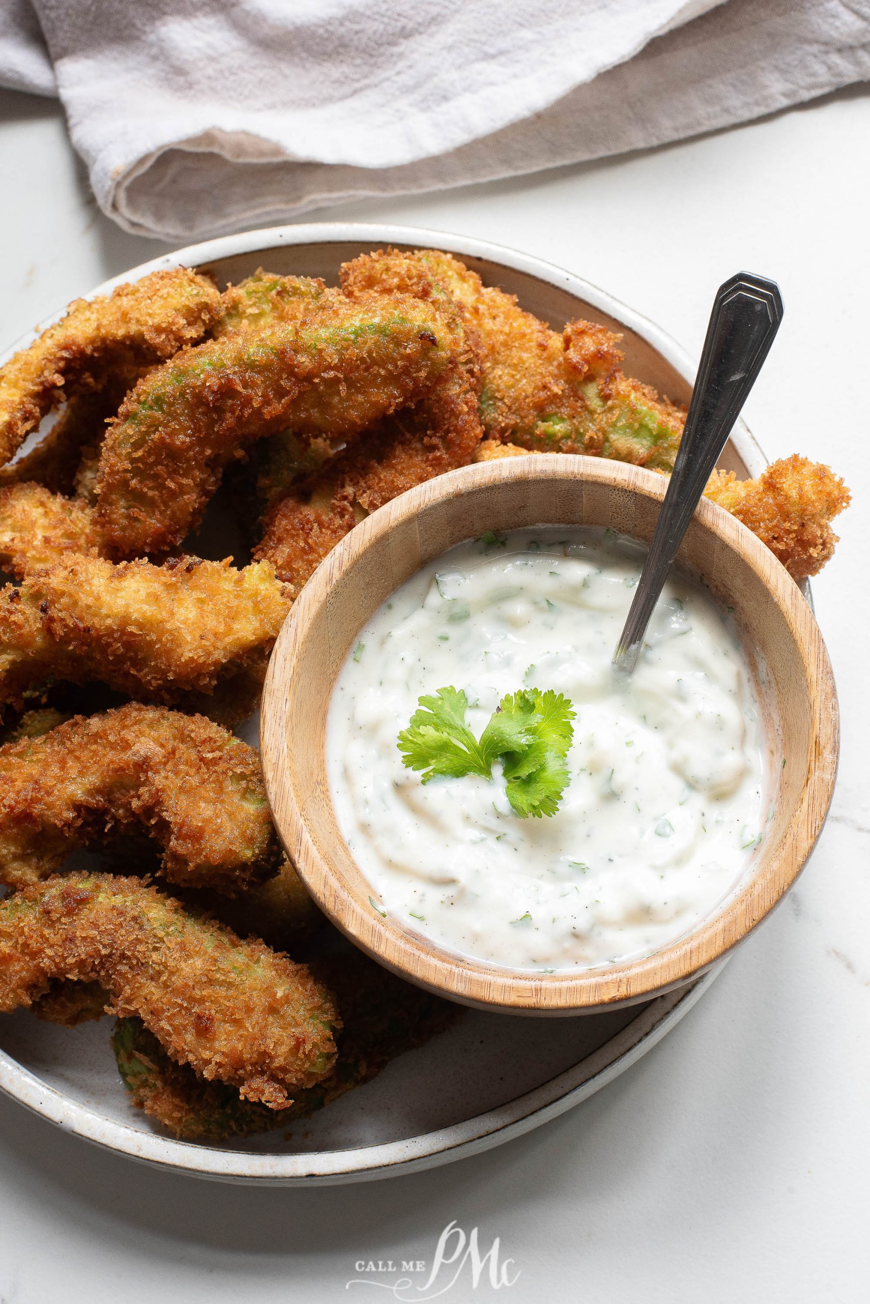 Fried green beans with dipping sauce on a plate.