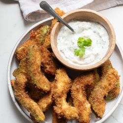 Fried okra with a dip on a plate.