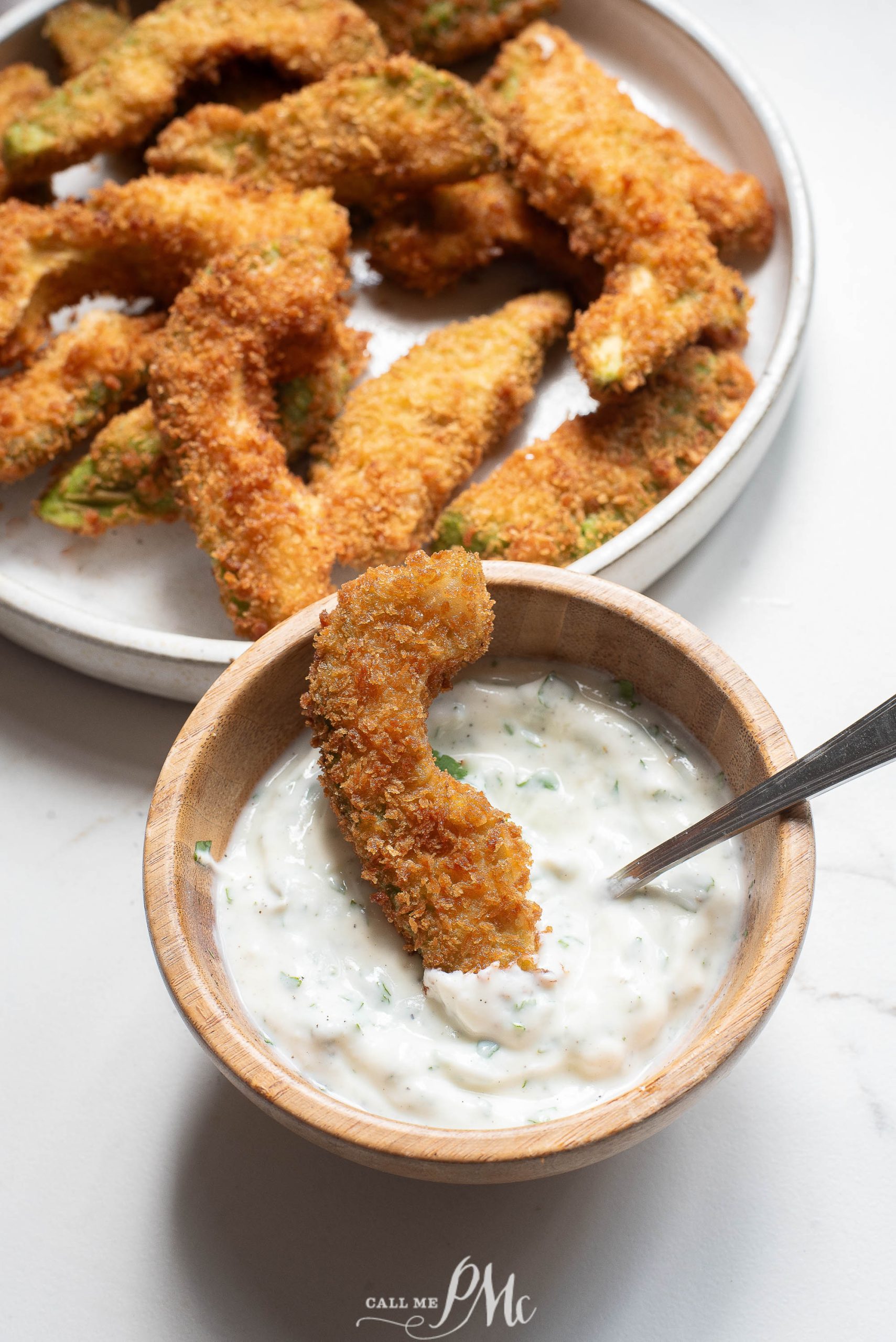 A bowl of fried avacado fries with dipping sauce.