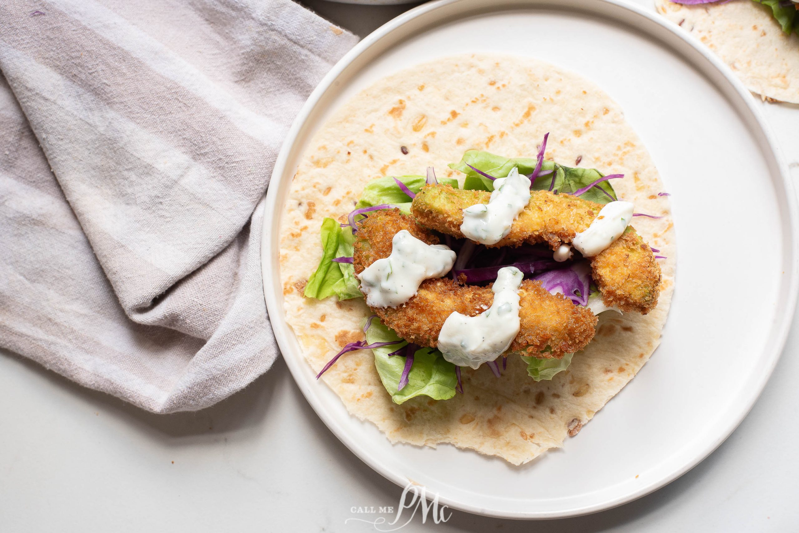 Oven-fried avocado tacos on a plate with salad and dressing.