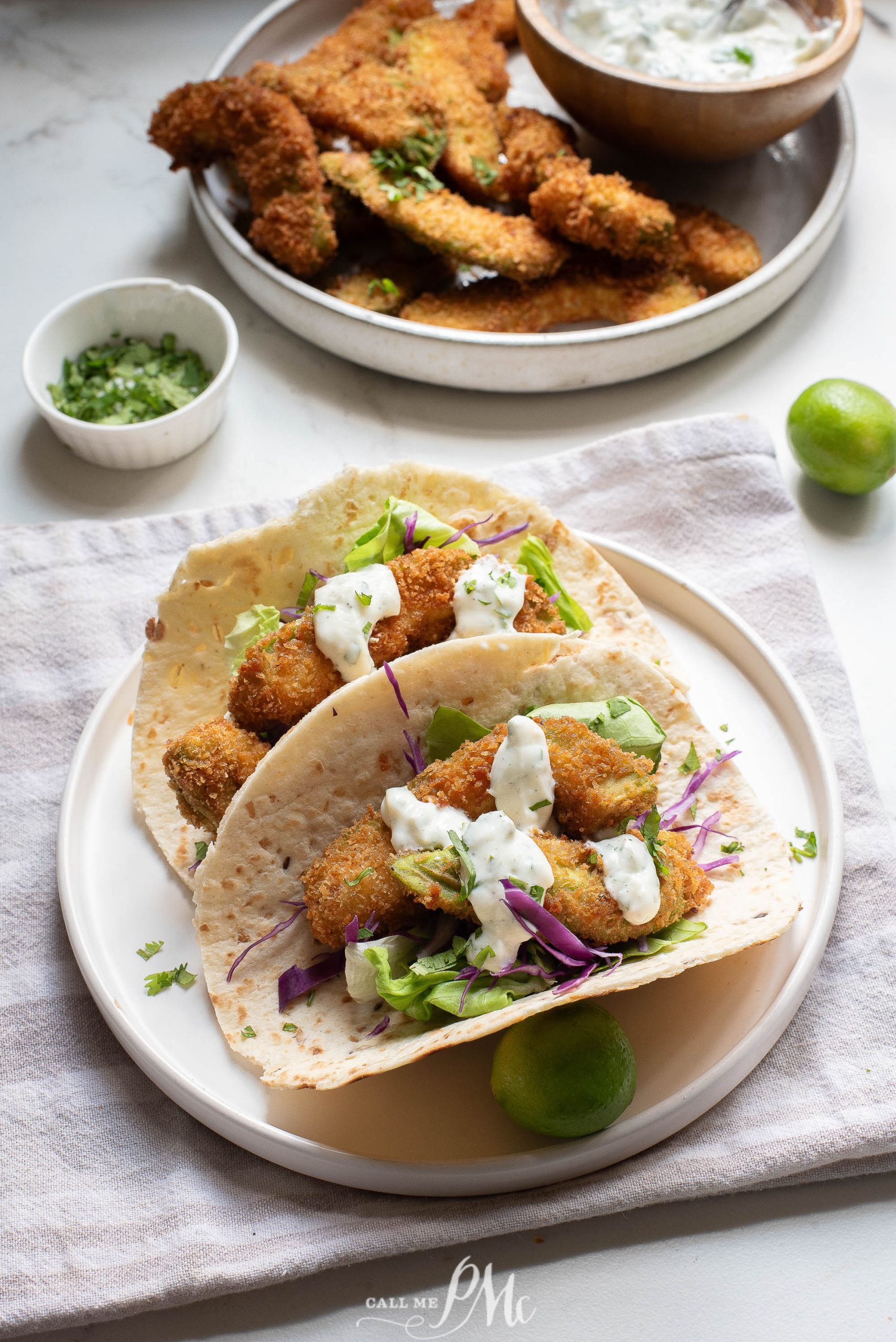 Oven-fried avocado tacos on a white plate with dipping sauce.