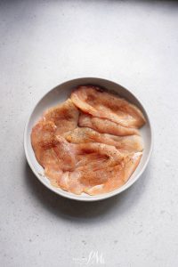 Chicken breasts on a plate on a white surface.