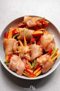 Chicken skewers with carrots and peppers on a plate.