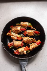 Chicken wraps in a skillet on a stove top.