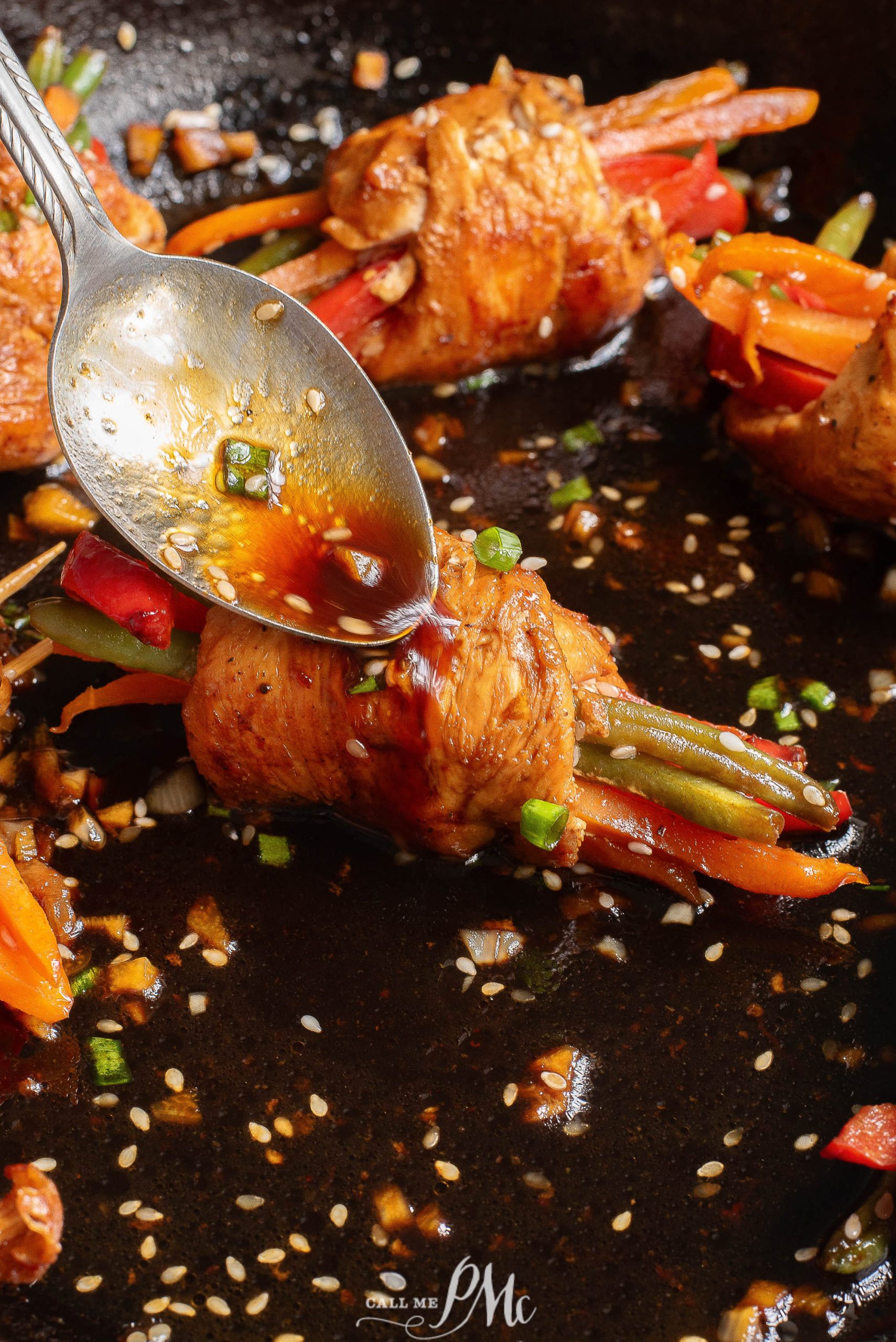 A spoon is being used to eat some chicken and vegetables in a skillet.