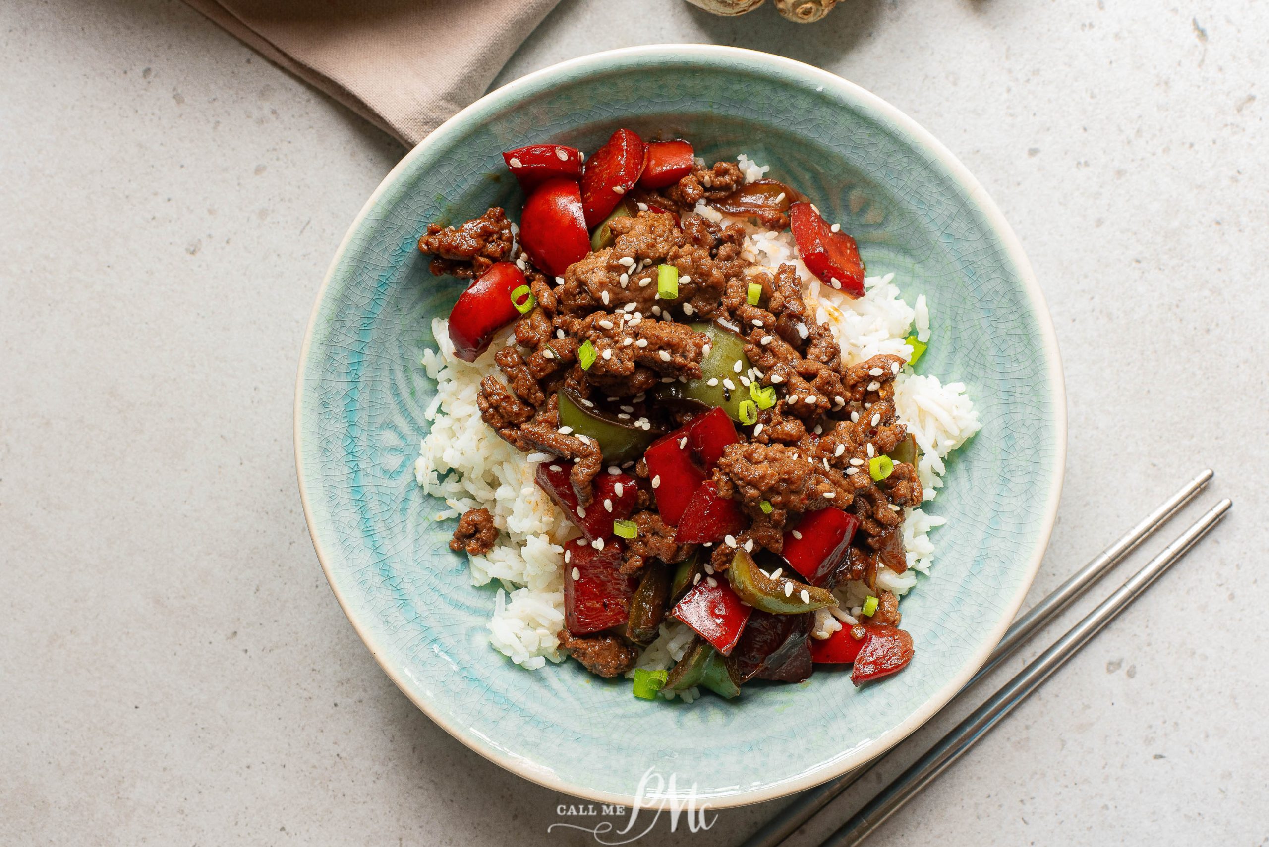 A bowl of beef stir fry with rice and peppers.