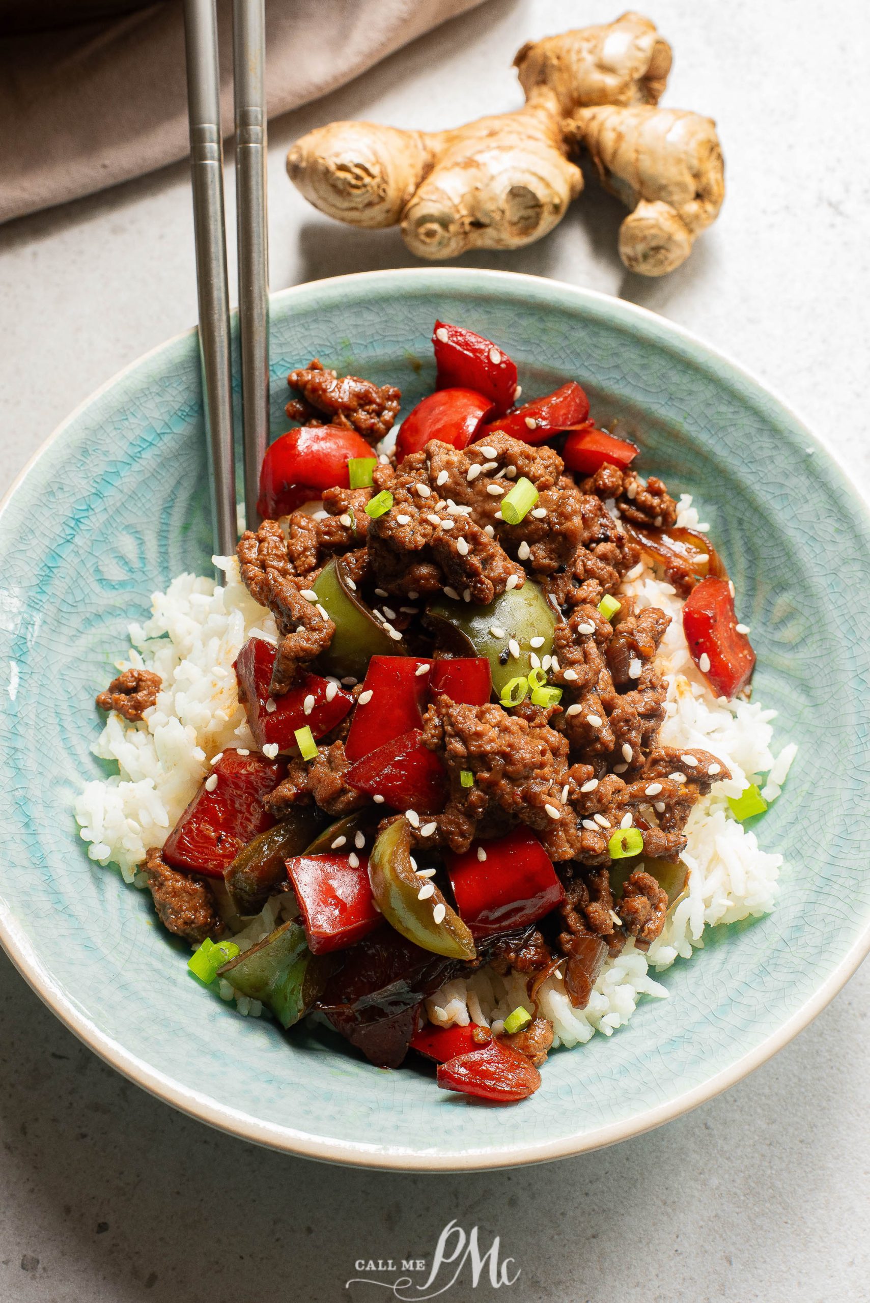 Chinese beef stir fry in a blue bowl with chopsticks.