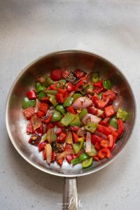 A frying pan filled with red peppers and onions.