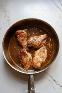 Chicken breasts in a frying pan with sauce.