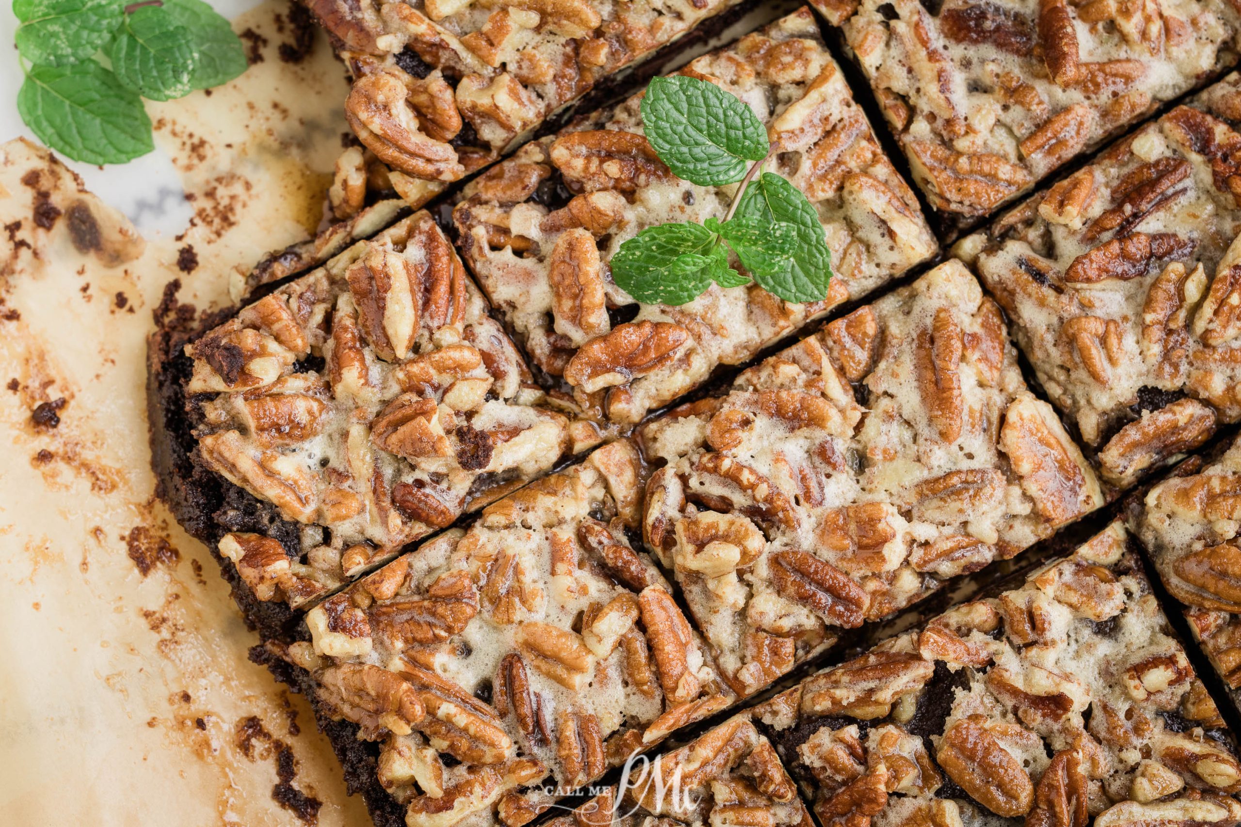 Brownies with pecans and mint on a baking sheet.