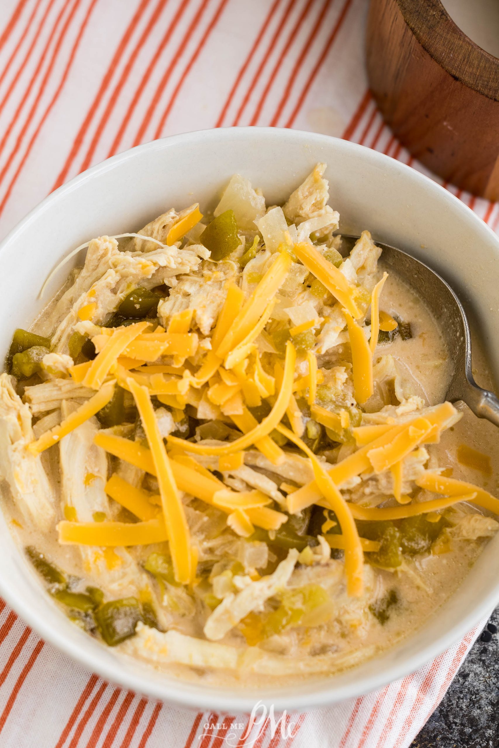 Chicken enchilada soup in a bowl with cheese and green onions.