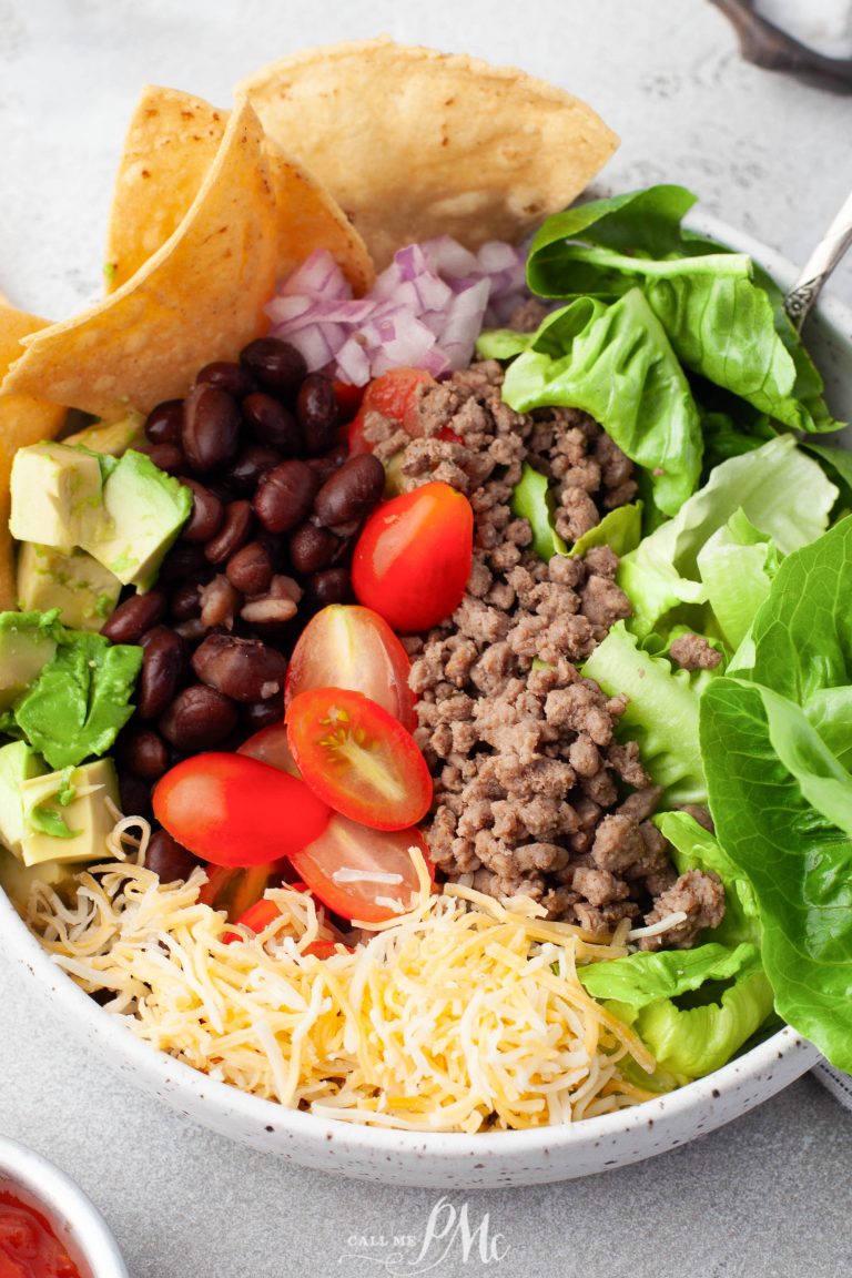 A bowl of mexican salad with meat, lettuce, tomatoes and tortillas.