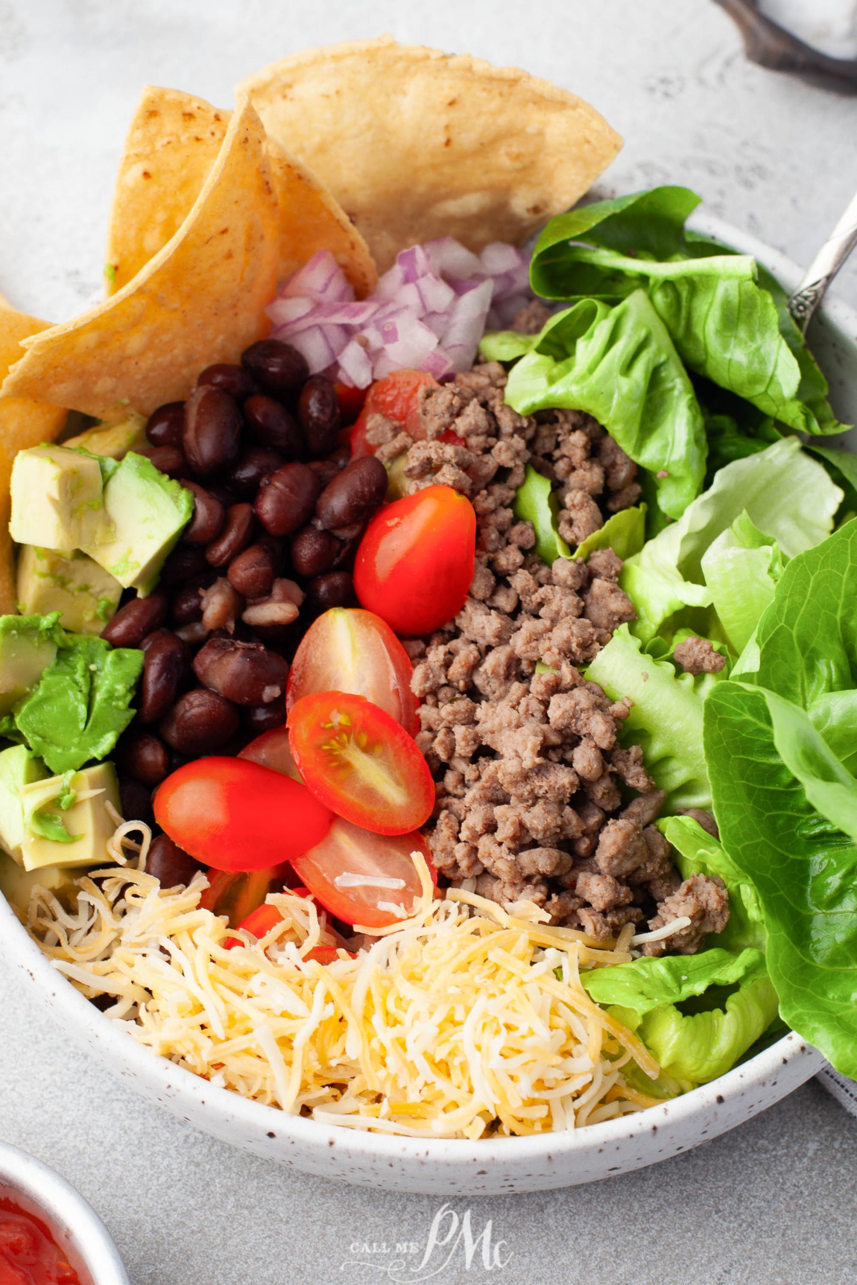 A bowl of meat, lettuce, tomatoes and tortillas.