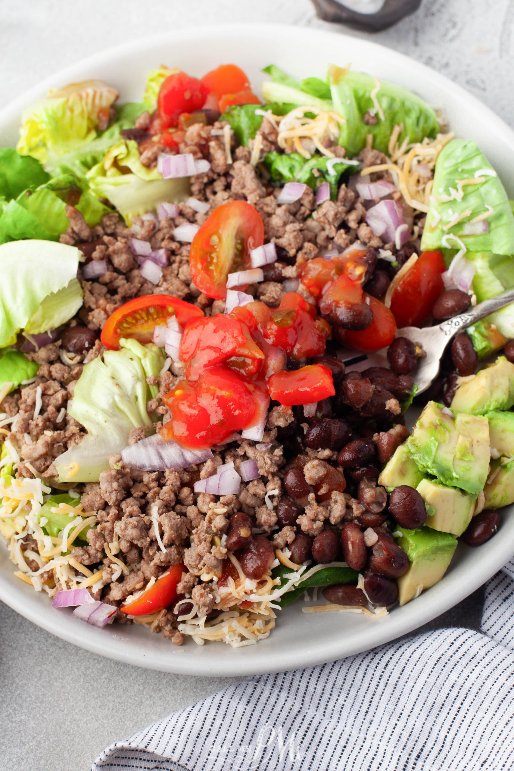 A bowl of meat, tomatoes and avocados.