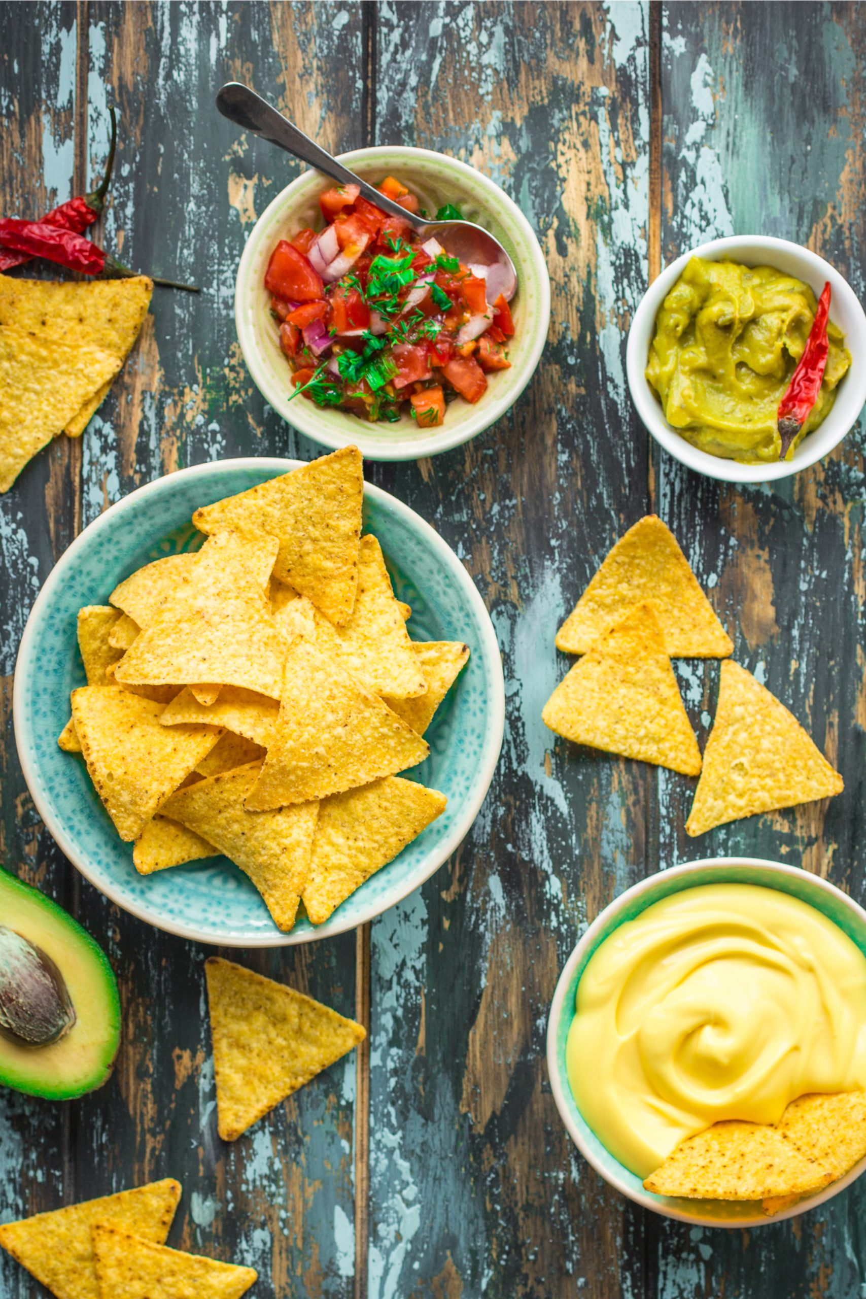 Guacamole, chips and salsa on a wooden table.