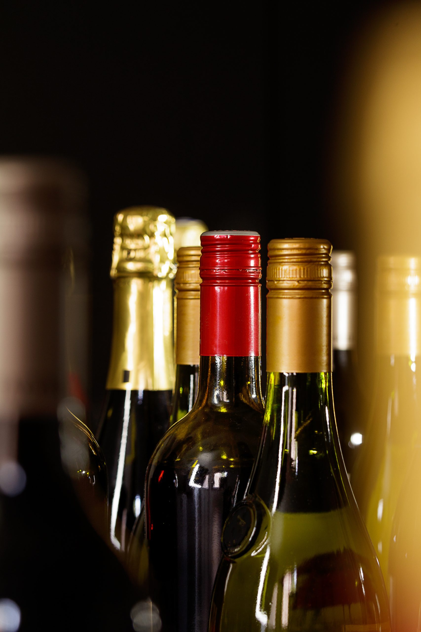 A row of wine bottles on a black background.