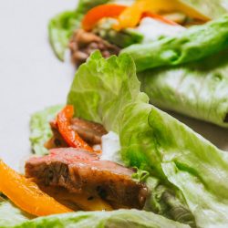 A plate of lettuce wraps with meat and peppers.
