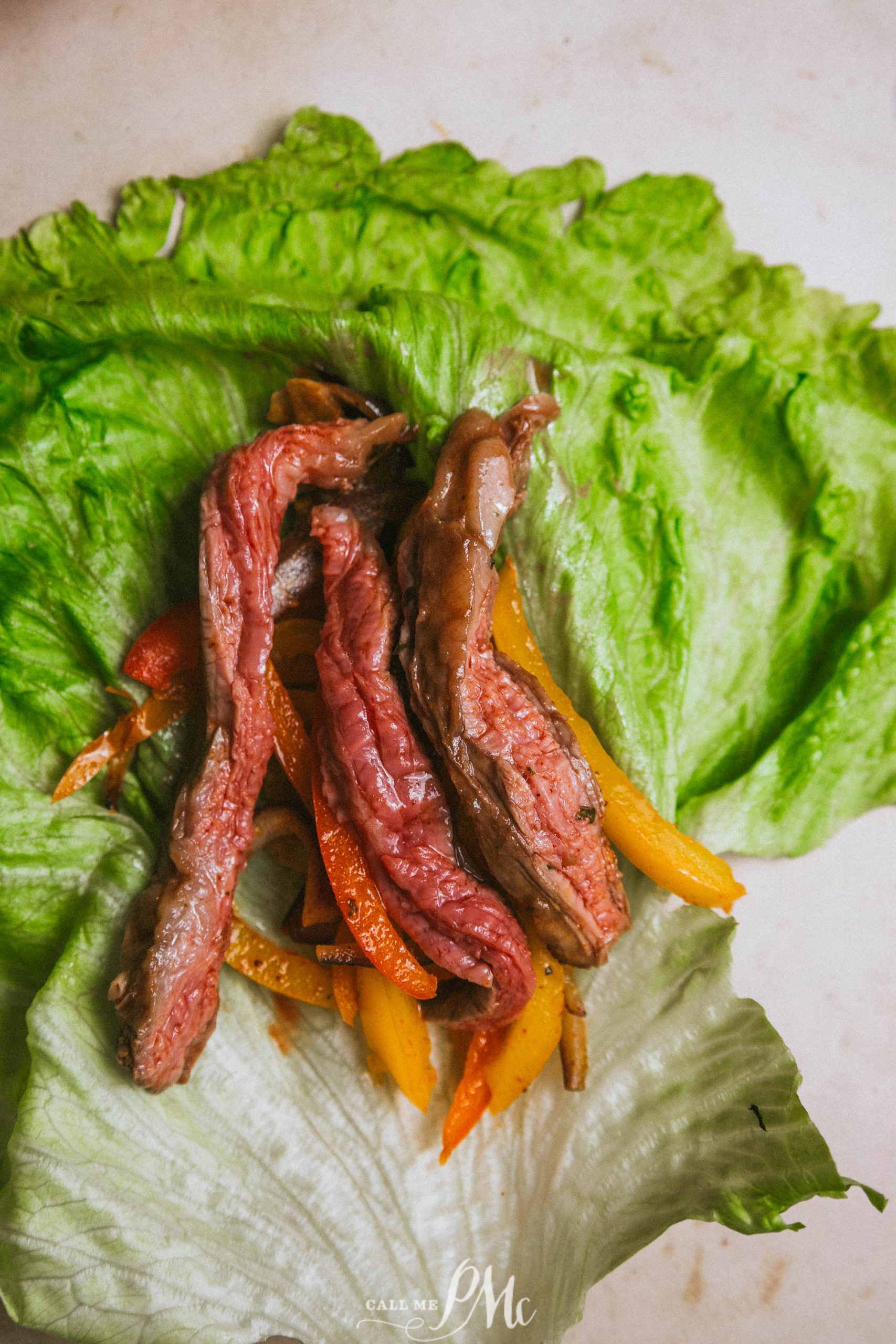 A lettuce wrap with steak and peppers on it.