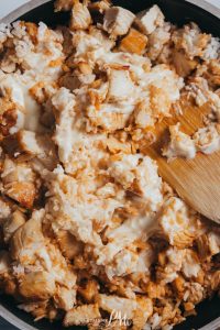 Chicken and rice in a pan with a wooden spoon.