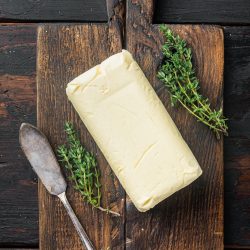 Butter on a wooden cutting board with thyme.