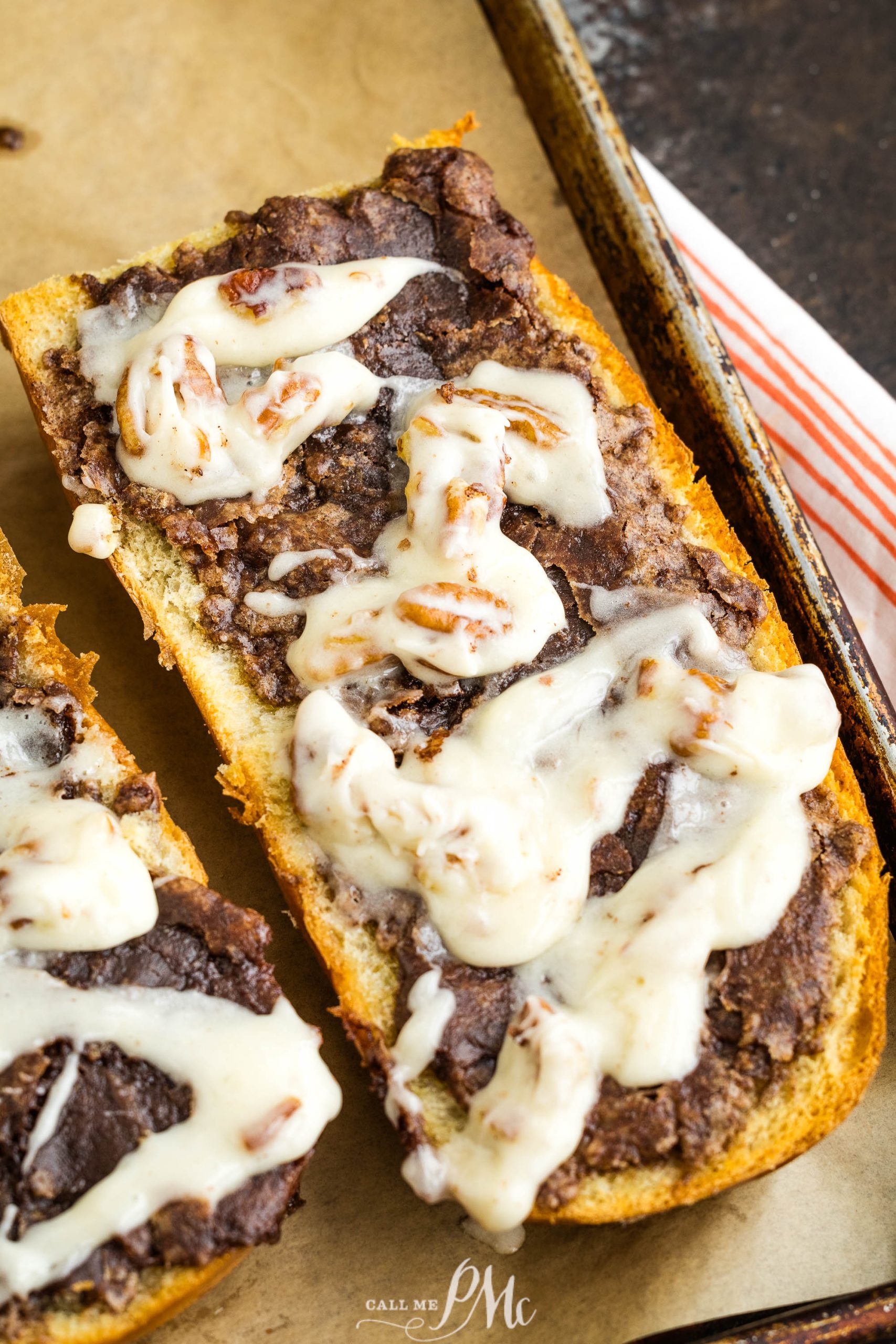 Two slices of bread with cheese and sauce on a baking sheet.