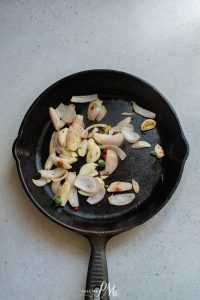 A frying pan with garlic and onions in it.