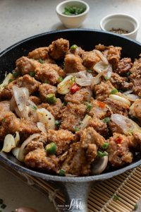 Fried chicken in a skillet with onions and peppers.
