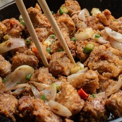 Chinese fried chicken in a skillet with chopsticks.