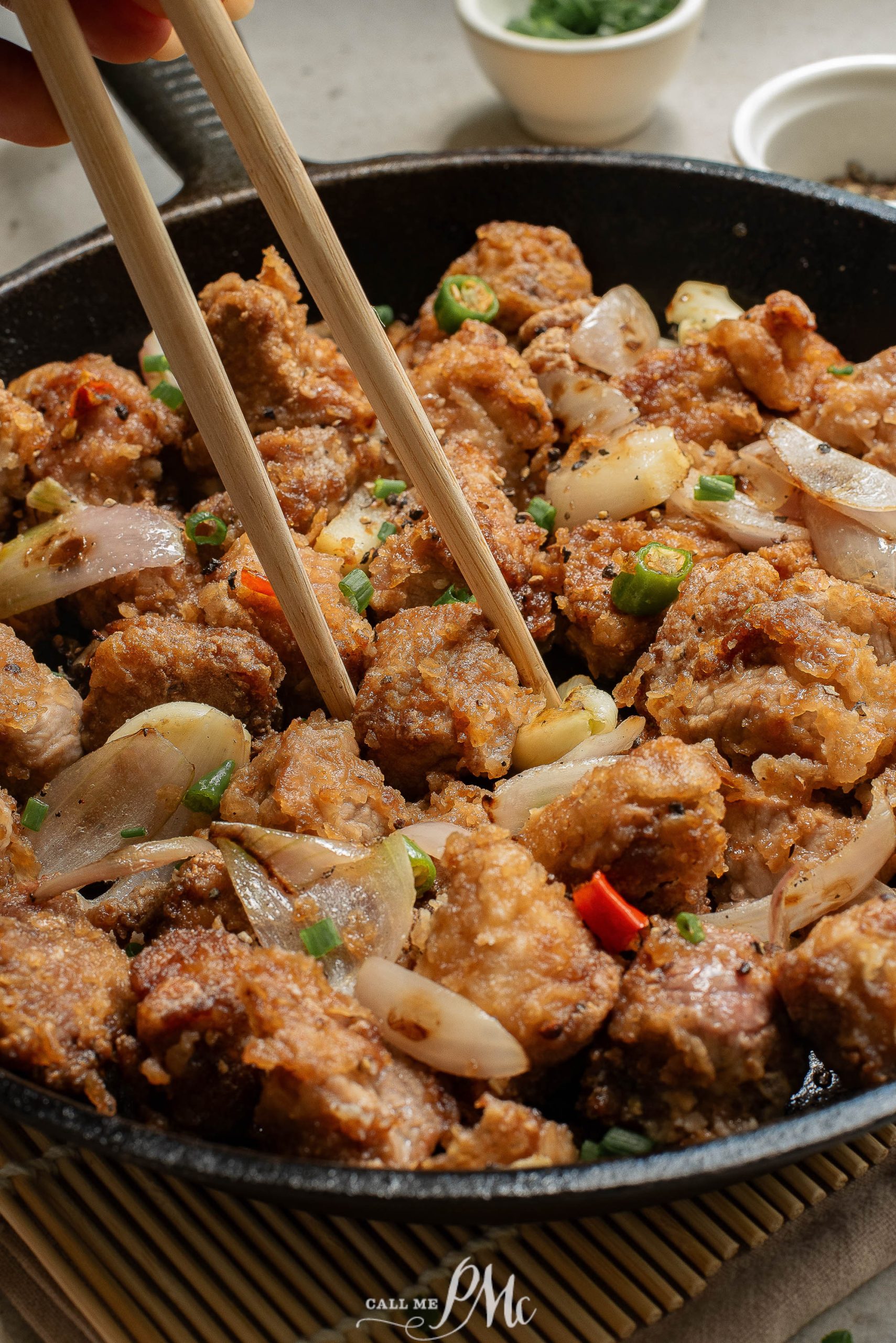 Salt Pepper Pork Chop Bites in a skillet with chopsticks.