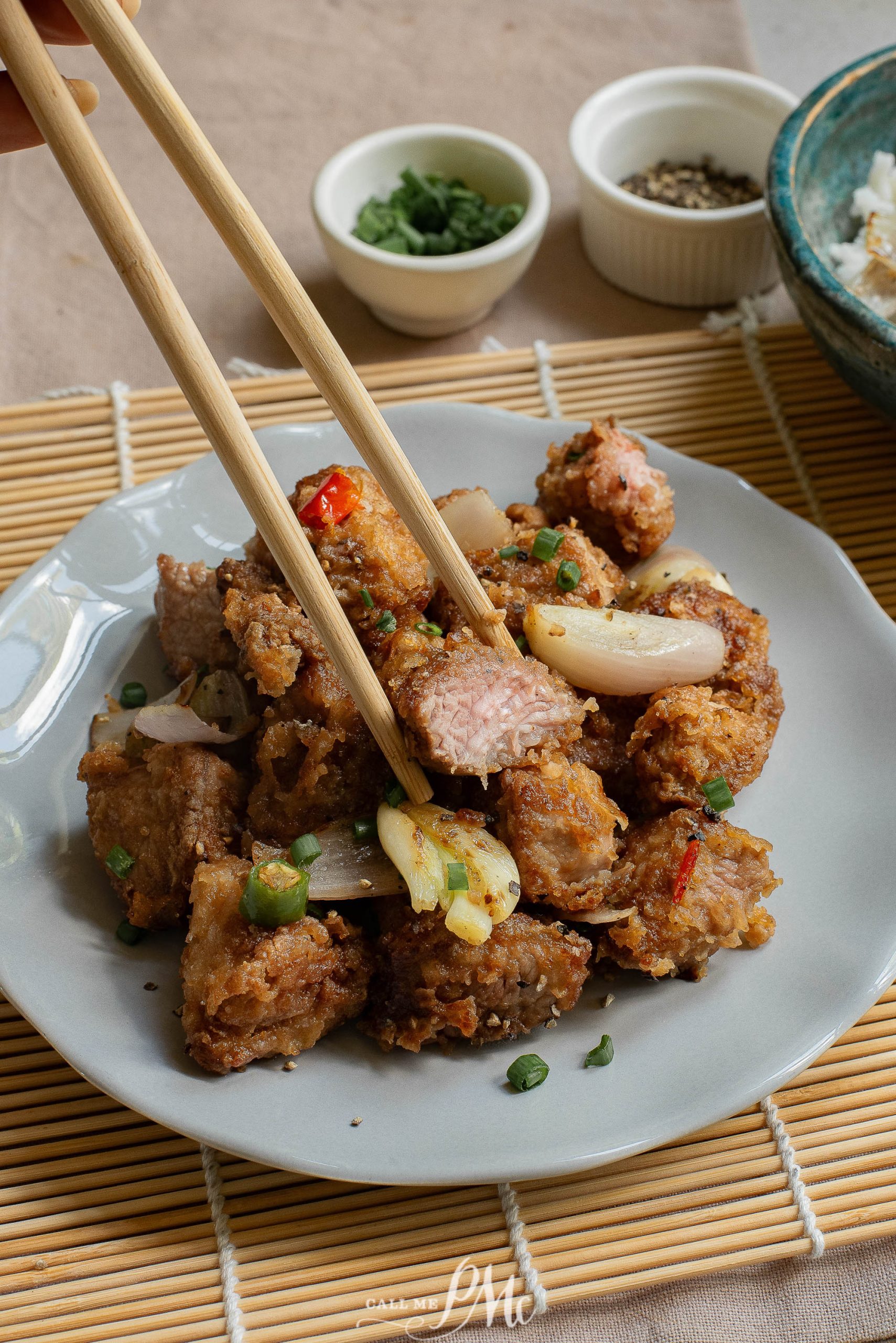 A plate of meat with chopsticks on it.