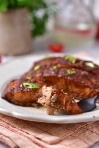 A piece of salmon on a plate with a fork.