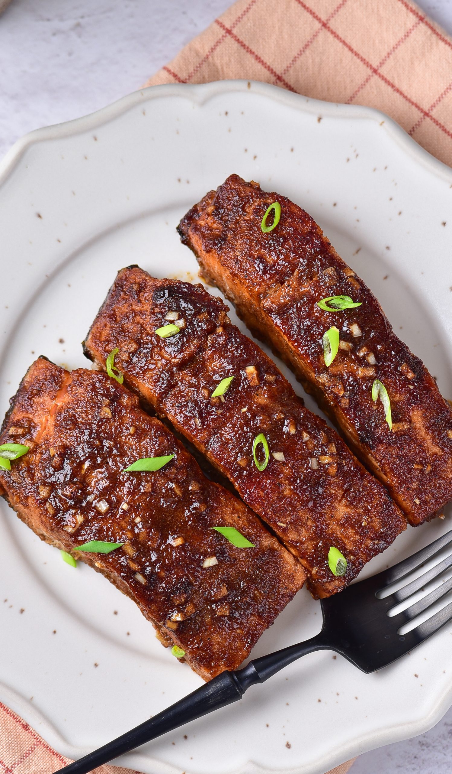 A plate with three pieces of grilled salmon on it.