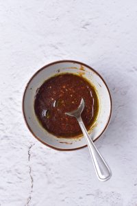 A bowl of sauce with a spoon in it.