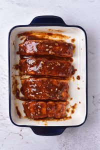 Bbq ribs in a baking dish on a white background.
