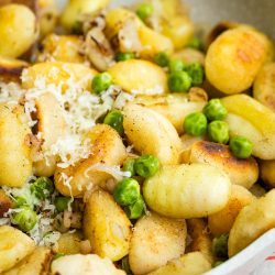 Gnocchi with peas and parmesan in a skillet.