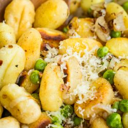 Gnocchi with peas and parmesan in a white bowl.