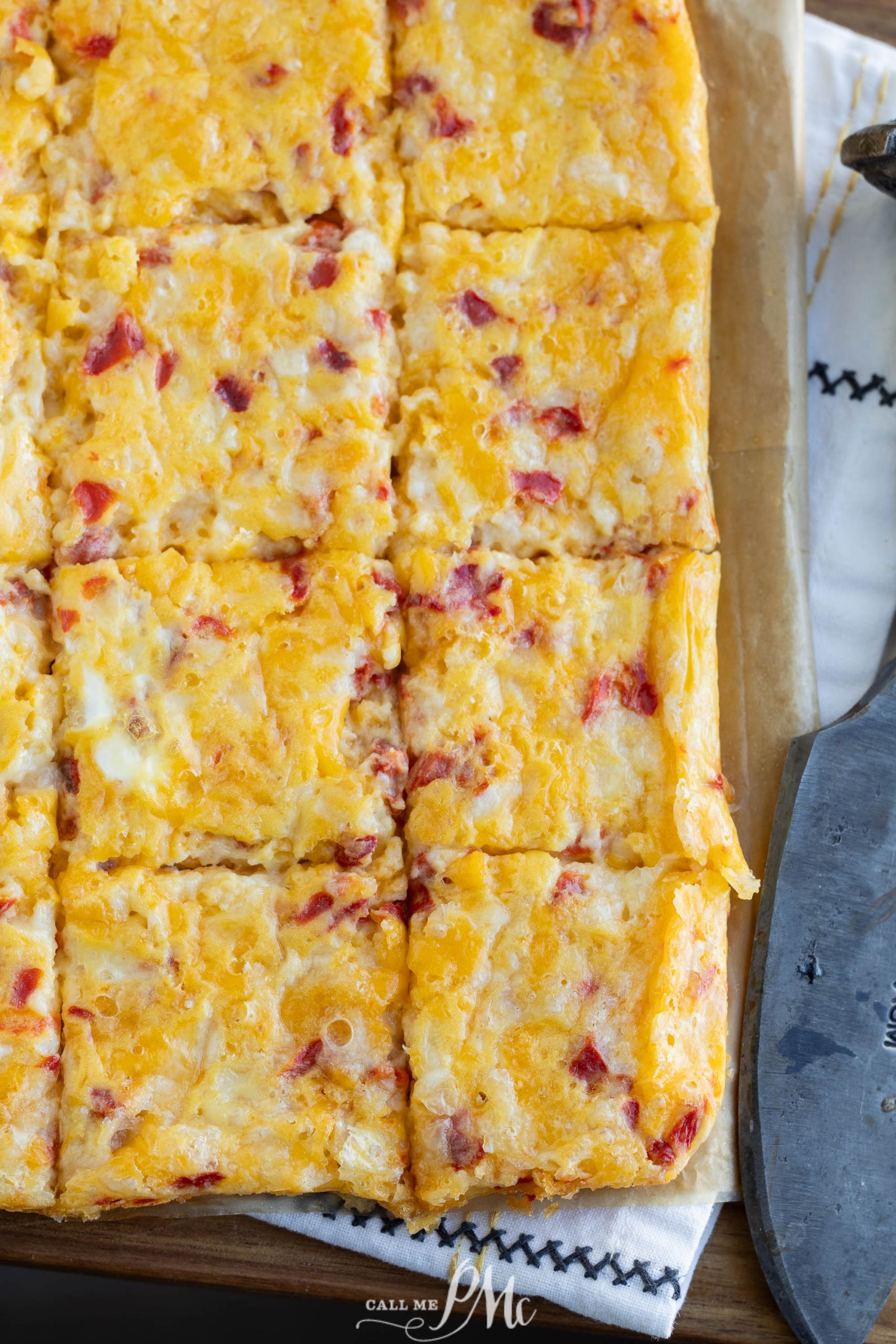 A square of cheese and bacon on top of a cutting board.