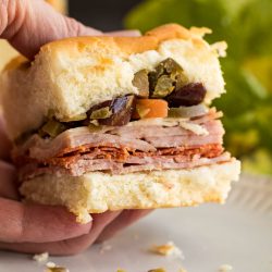 A person holding a sandwich on a plate.