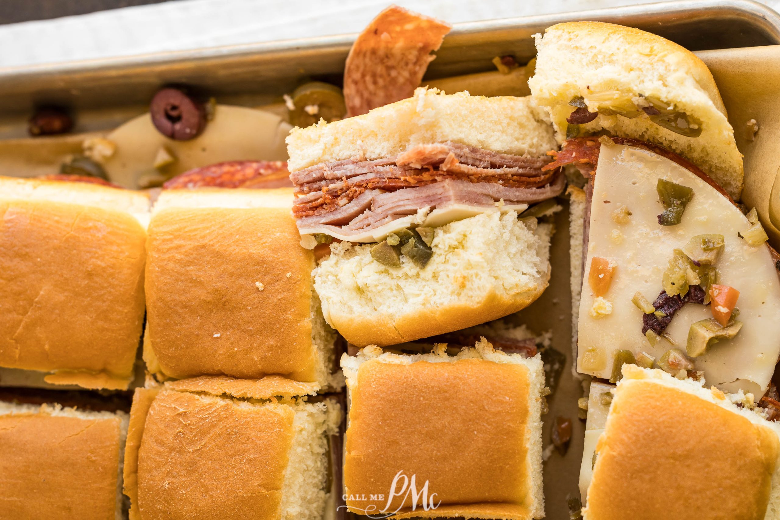 A tray of meat and cheese sliders on a baking sheet.