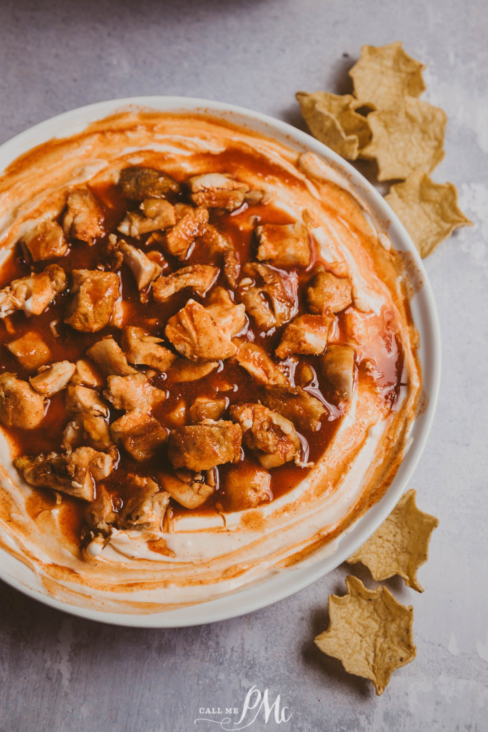 A bowl of dip with chicken and sauce on it.