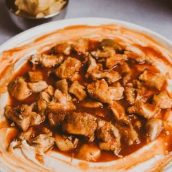 A bowl of chicken dip with chips and salsa.