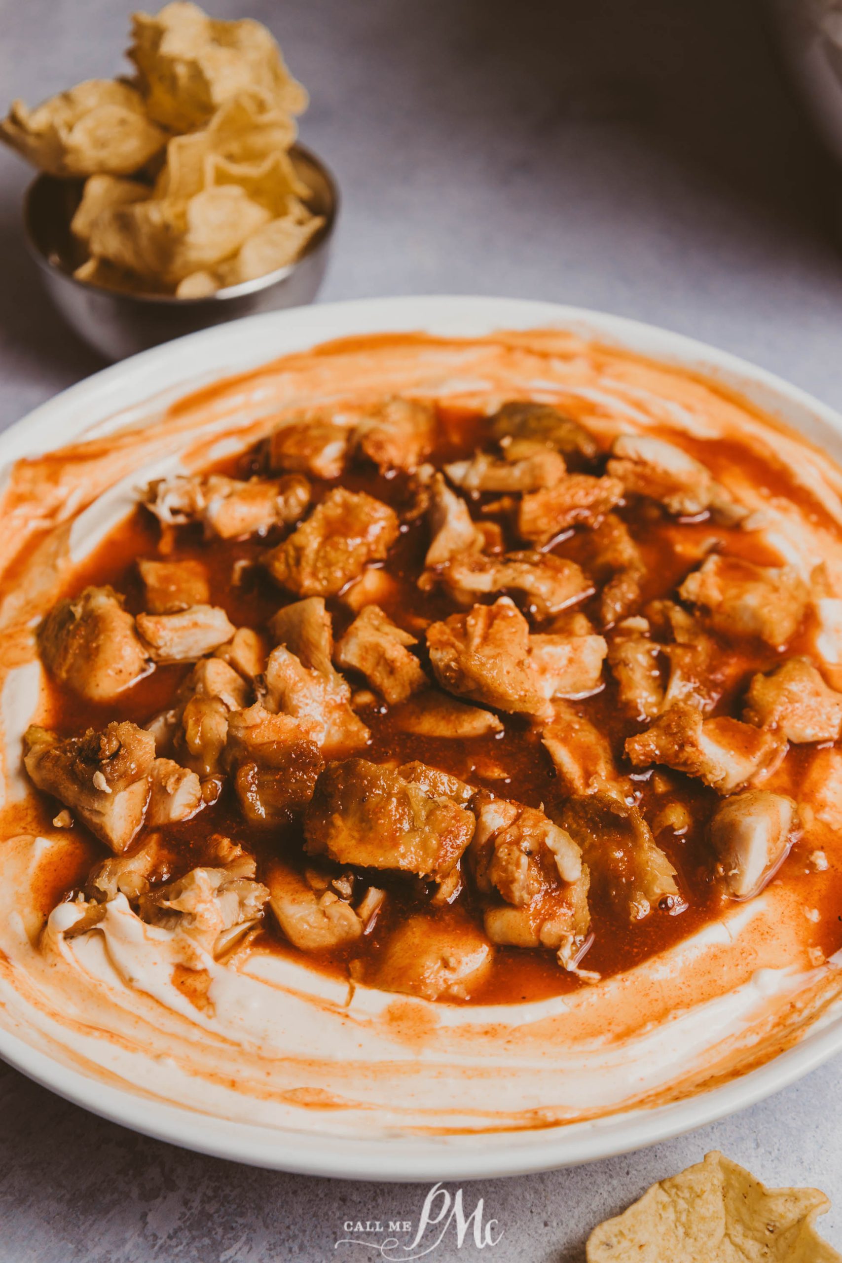 A bowl of chicken dip with chips and salsa.